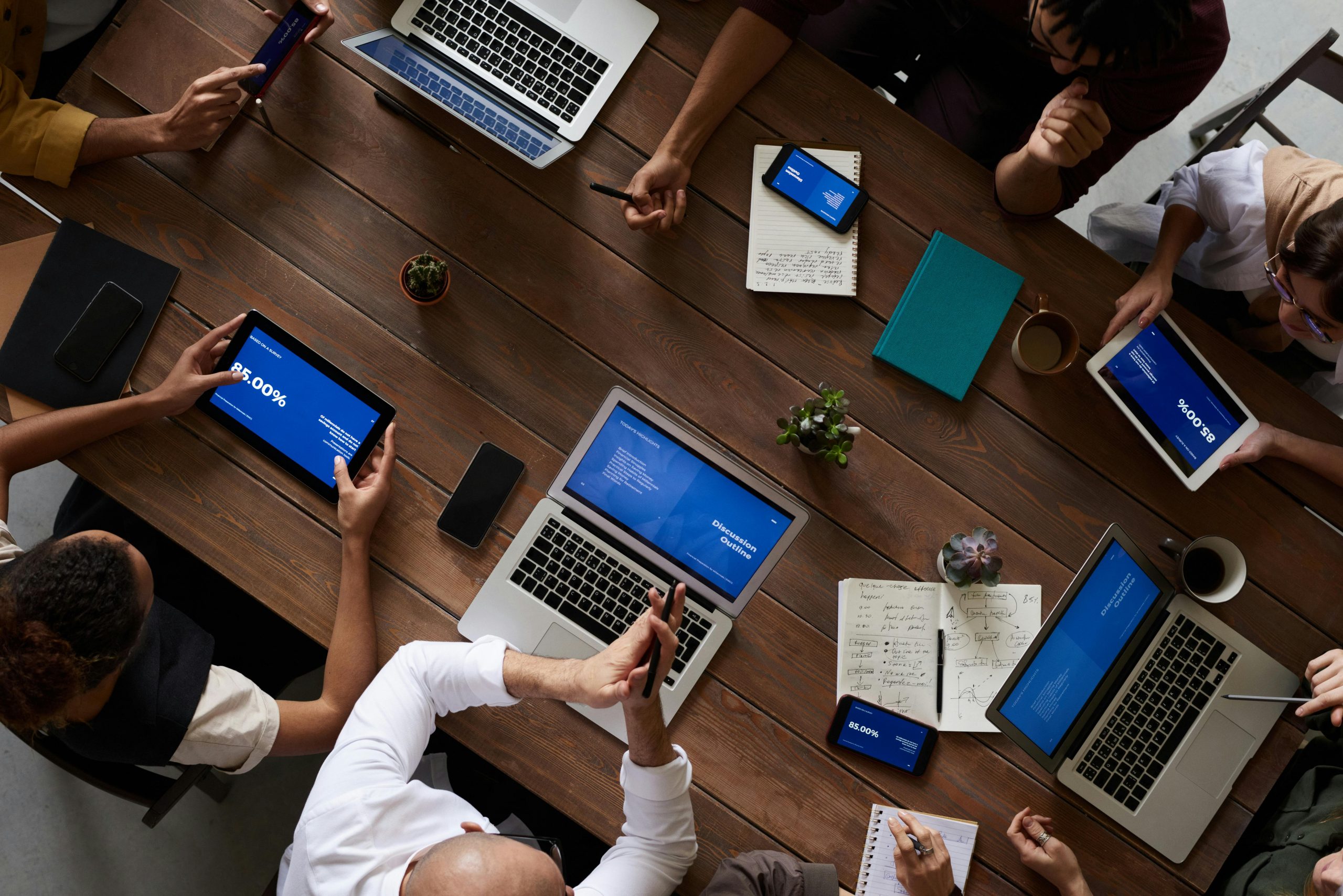 People collaborating around a table with laptops and documents